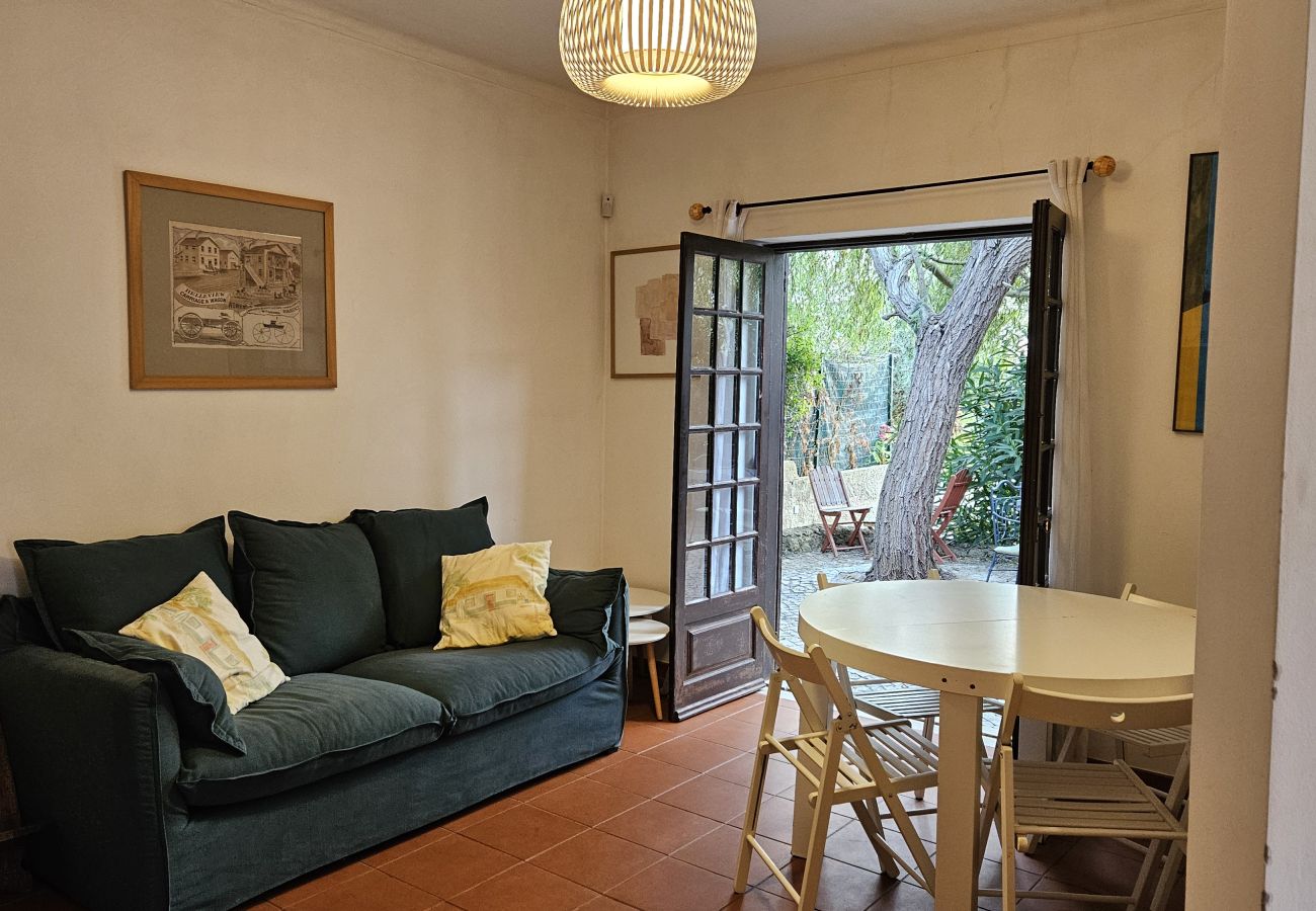 Sala de estar espaçosa, com sofá, mesa de jantar e vista para o jardim. 