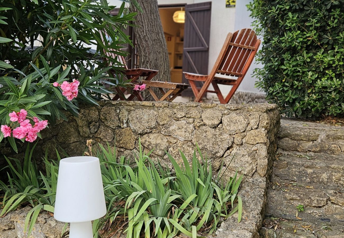 Espaço relaxante no jardim, com cadeiras de madeira e plantas em tons vibrantes. 