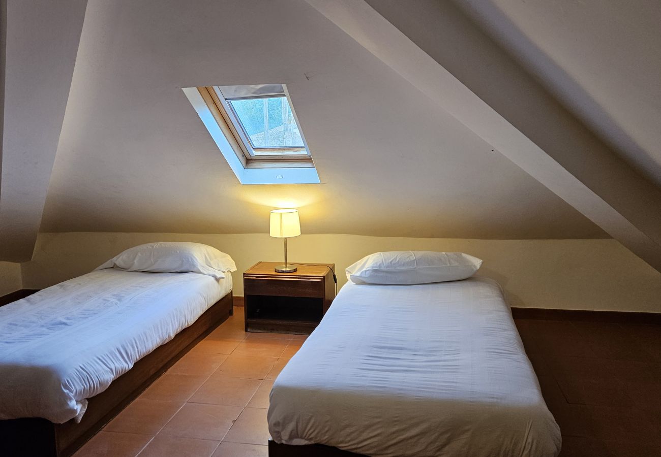 Quarto charmoso no sótão, com duas camas separadas, iluminação suave e claraboia. 