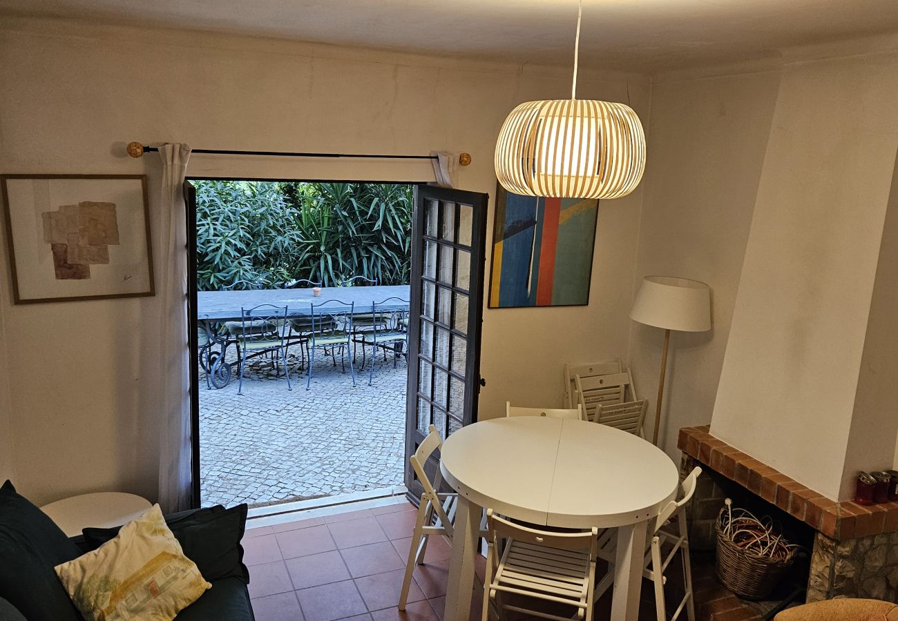 Sala de jantar aconchegante, com mesa redonda e portas de vidro abertas para o jardim