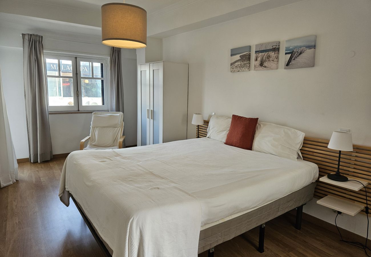 Quarto espaçoso com cama de casal, lençóis claros e janelas amplas. 