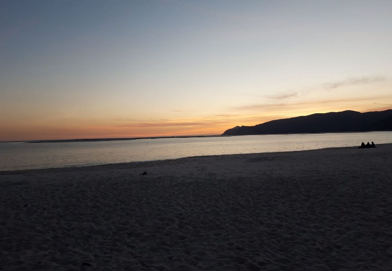 Praia com areias douradas, capturada ao pôr do sol com tons quentes no horizonte.