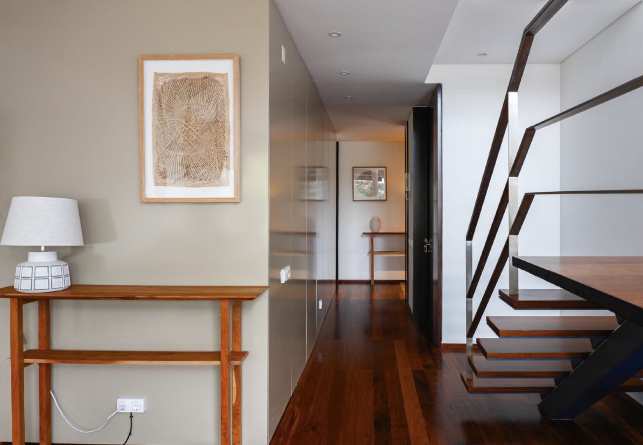 Hall com piso de madeira, escadas modernas e decoração minimalista na Pool Beach & Golf Troia.