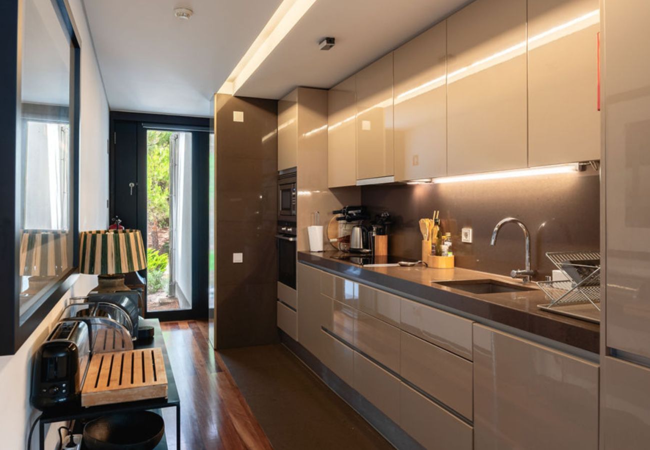 Cozinha equipada com armários elegantes, eletrodomésticos modernos e iluminação embutida na Pool Beach & Golf Troia.