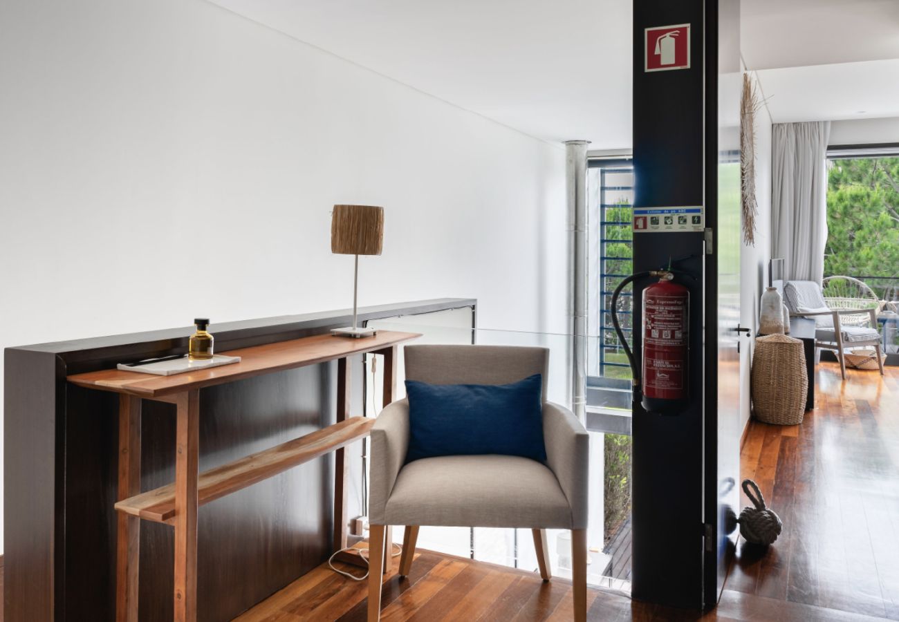 Hall decorado com mobiliário minimalista, cadeira confortável e iluminação natural na Pool Beach & Golf Troia.