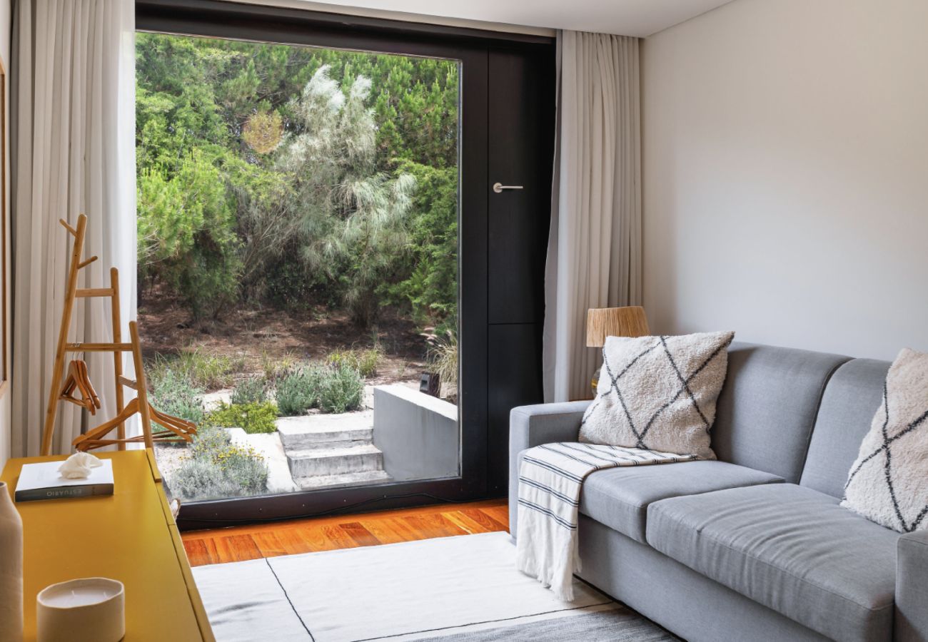 Sala de estar com sofá cinza, mesa de centro e vista para o terraço na Pool Beach & Golf Troia.