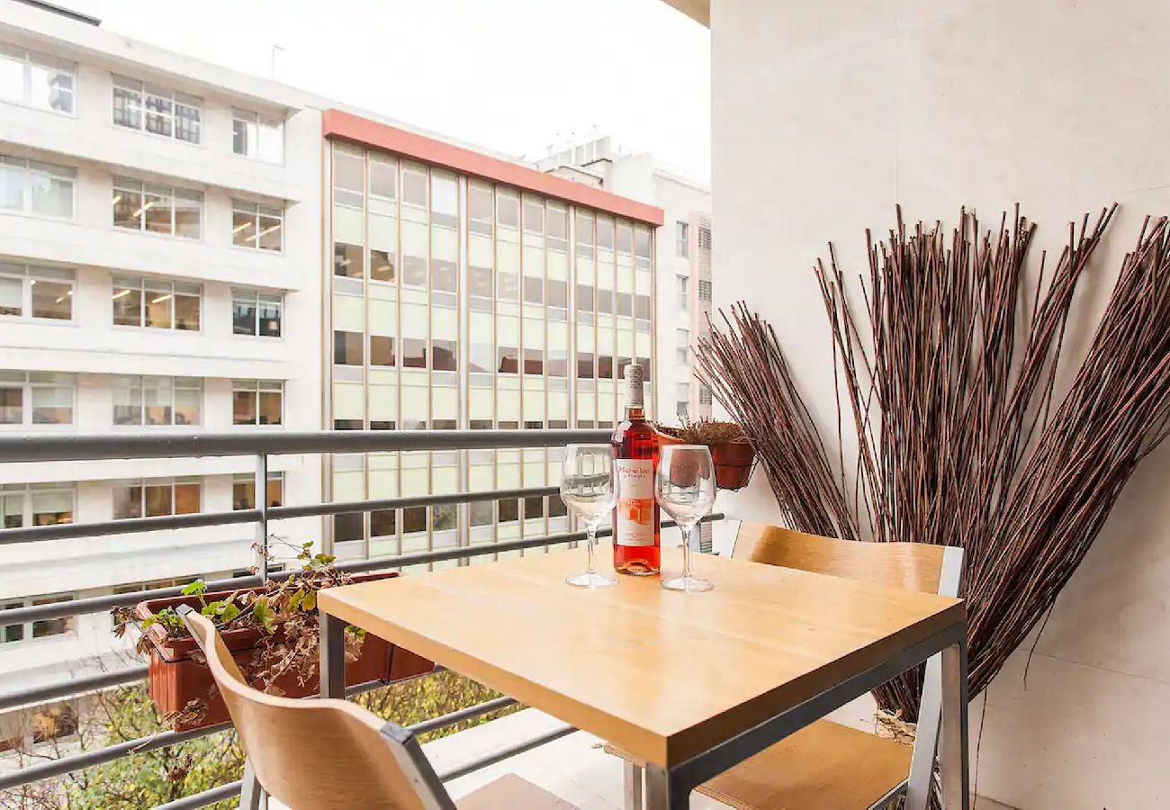 Varanda espaçosa com vista para a cidade, decorada com plantas e mobília aconchegante.