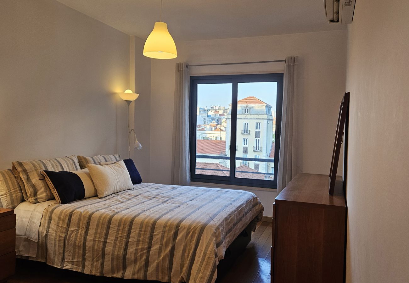 Cama grande com cabeceira elegante, almofadas contrastantes e ambiente sofisticado.