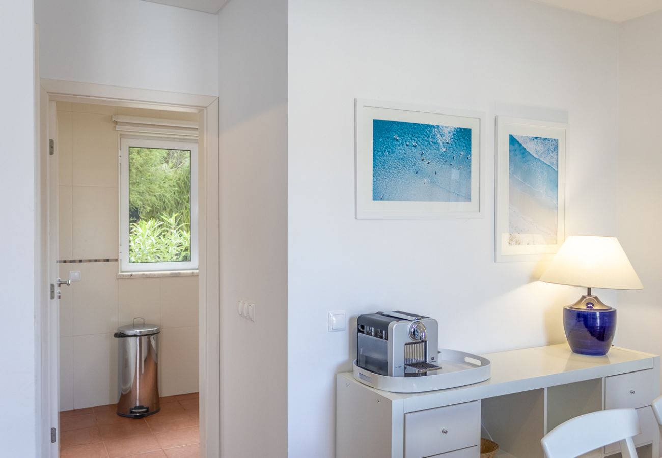 Sala de jantar com aparador branco, cafeteira, luminária e quadros decorativos na parede.