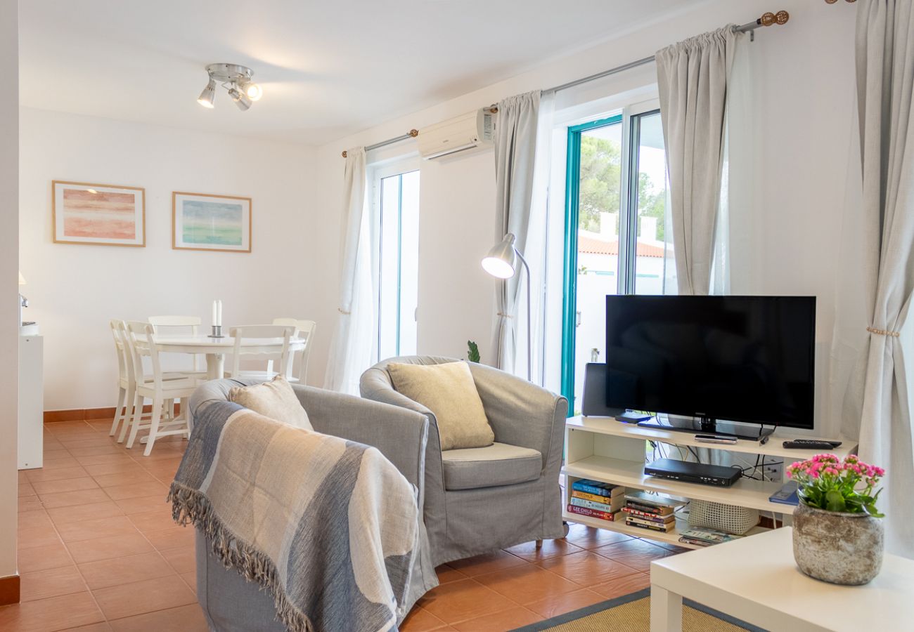 Sala com sofá azul, televisão e janelas amplas com luz natural.