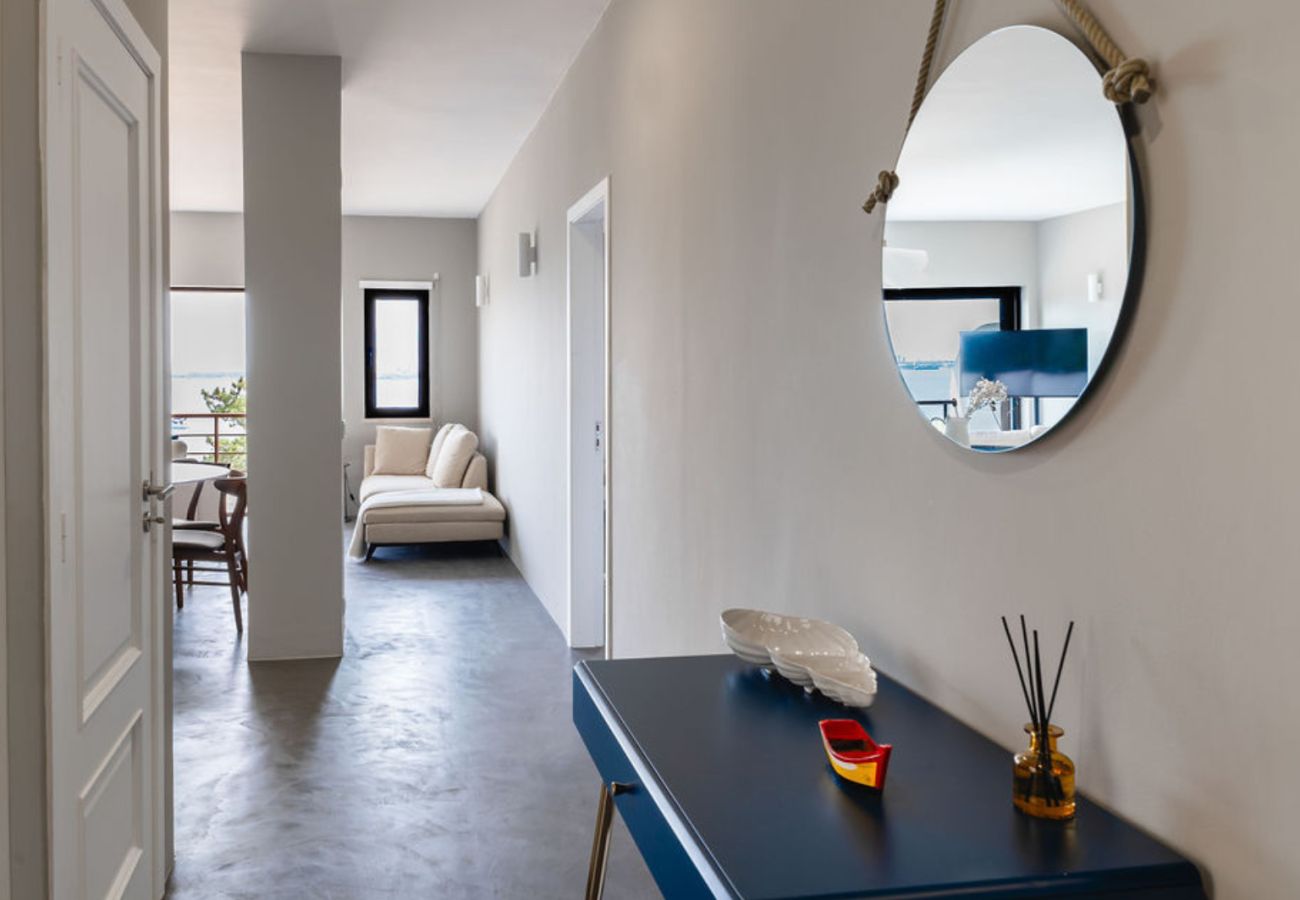 Aparador azul com objetos decorativos, incluindo um espelho redondo pendurado na parede, em um ambiente moderno e iluminado.
