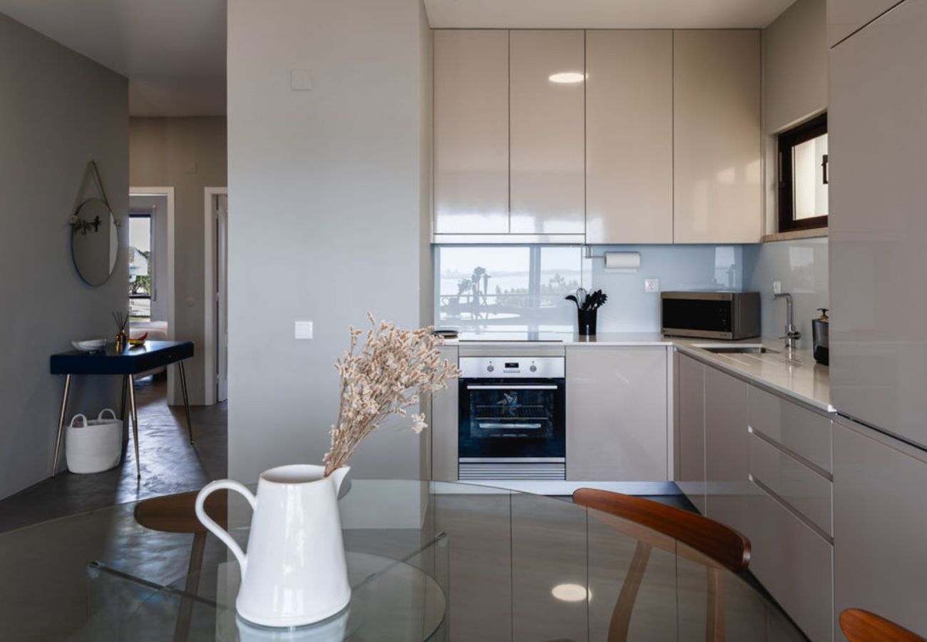 Cozinha planejada com armários brilhantes, eletrodomésticos embutidos e bancada funcional, integrada a uma sala de jantar elegante.