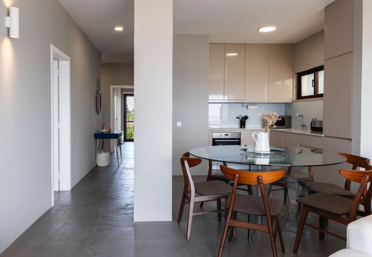 Cozinha sofisticada com armários embutidos, bancada funcional e mesa de vidro com cadeiras elegantes, em ambiente integrado à sala.