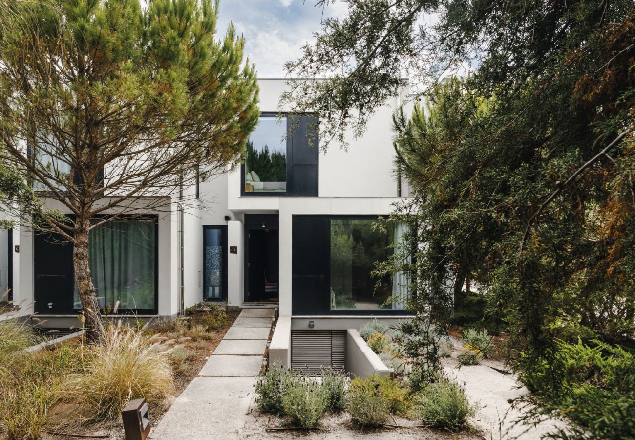 Fachada contemporânea com linhas minimalistas, rodeada por árvores e vegetação exuberante.