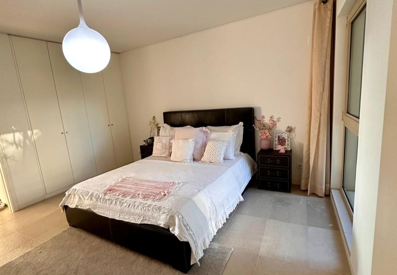 Quarto confortável e elegante com cama de casal, cabeceira estofada preta e roupa de cama branca com detalhes delicados. Acomodações bem iluminadas, c