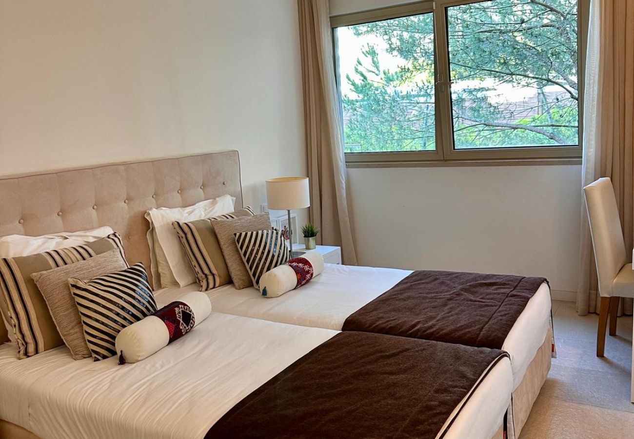 Quarto elegante e iluminado com duas camas de solteiro juntas, decorado em tons neutros. Conta com cabeceira estofada, almofadas decorativas, mesa de 