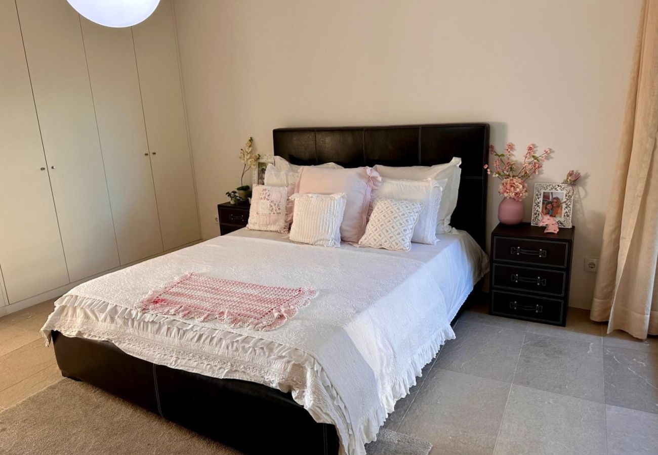 Quarto confortável e elegante com cama de casal, cabeceira estofada preta e roupa de cama branca com detalhes delicados. Acomodações bem iluminadas, c