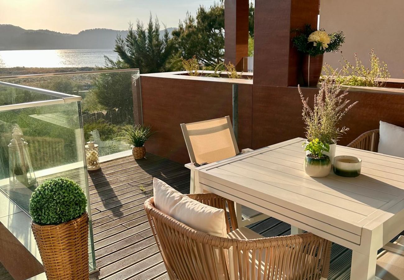 Terraço elegante com mesa e cadeiras, decoração sofisticada e vista panorâmica para o mar ao pôr do sol.