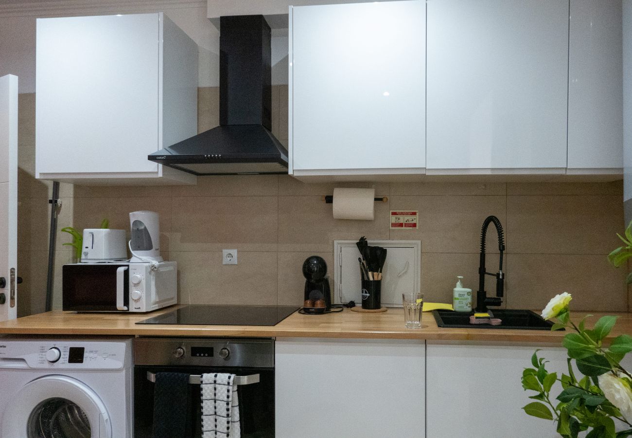 Banheiro com box de vidro preto, chuveiro moderno, pia branca de design e espelho redondo.