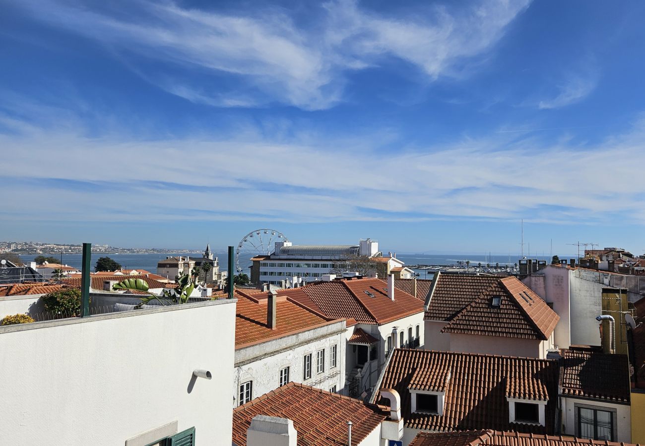Urban panorama with red roofs and blue sky, with the sea in the distance. 