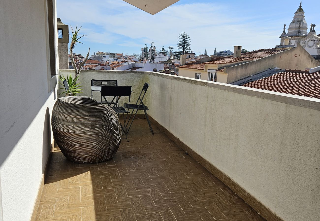 Balcony with decorative vase and open view of the city's rooftops and streets. 