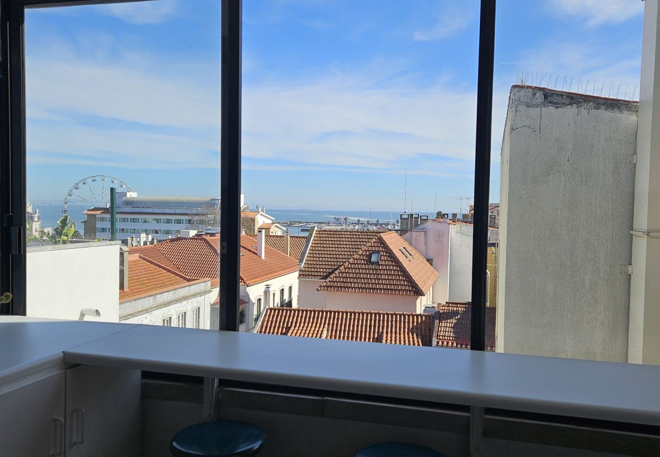 Large windows reveal the city's rooftops and blue skyline. 