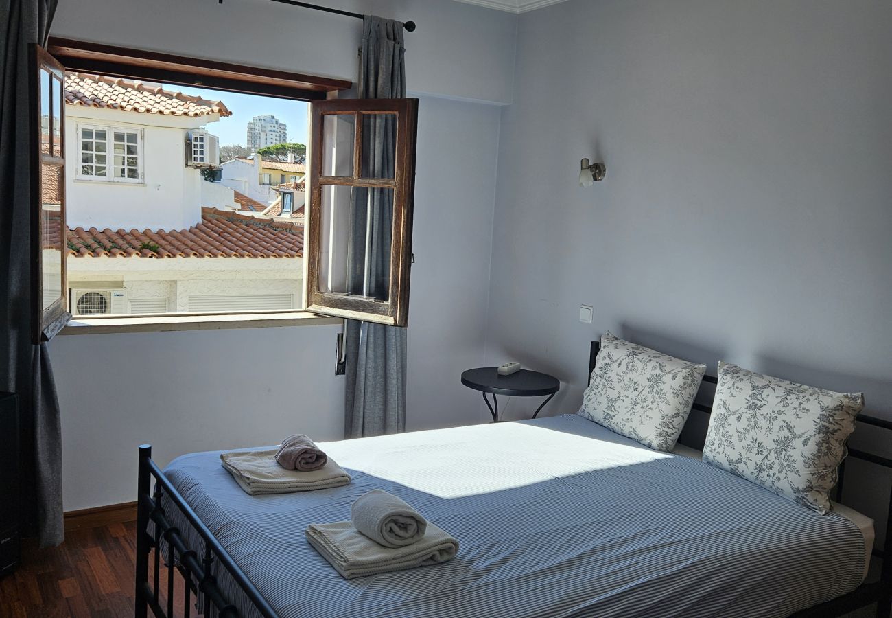 Double bed with white sheets, open windows and a view of the urban rooftops.