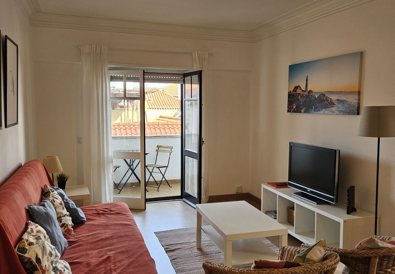 Cozy living room with a spacious sofa and glass doors leading to the balcony. 