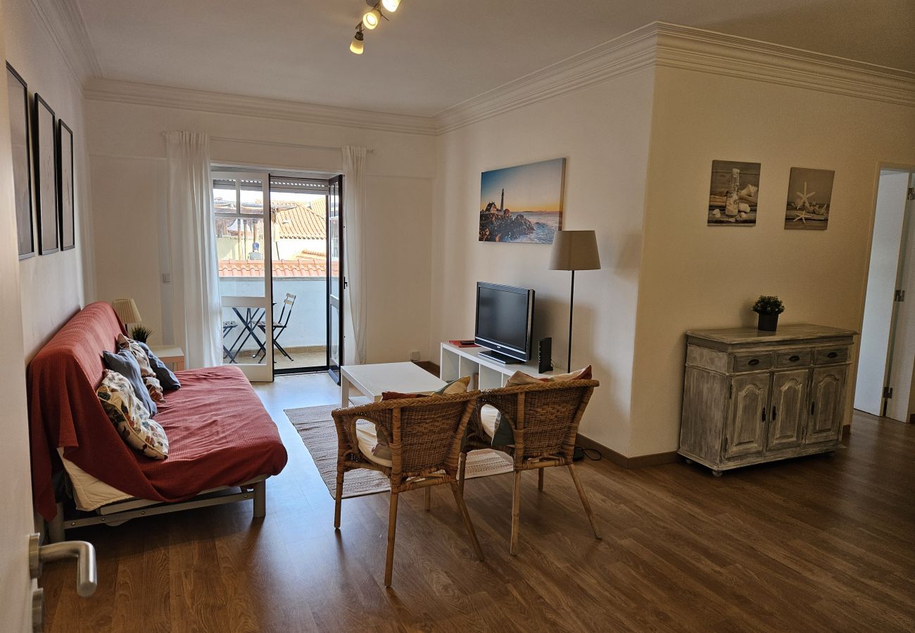 Cozy living room with a spacious sofa and glass doors leading to the balcony. 