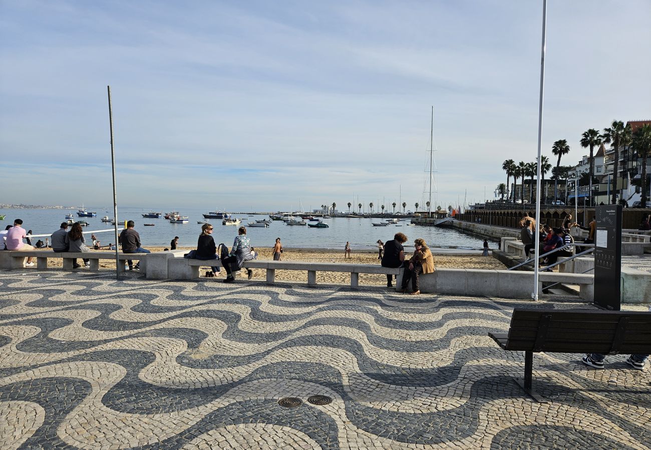 Seafront avenue in Cascais, with a promenade, palm trees, and a breathtaking view of the blue ocean. 