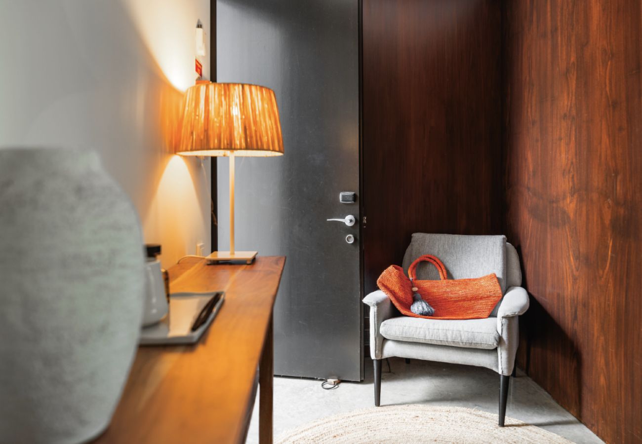 Entryway with a comfortable chair, decorative lamp, and side table at Pool Beach & Golf Troia.