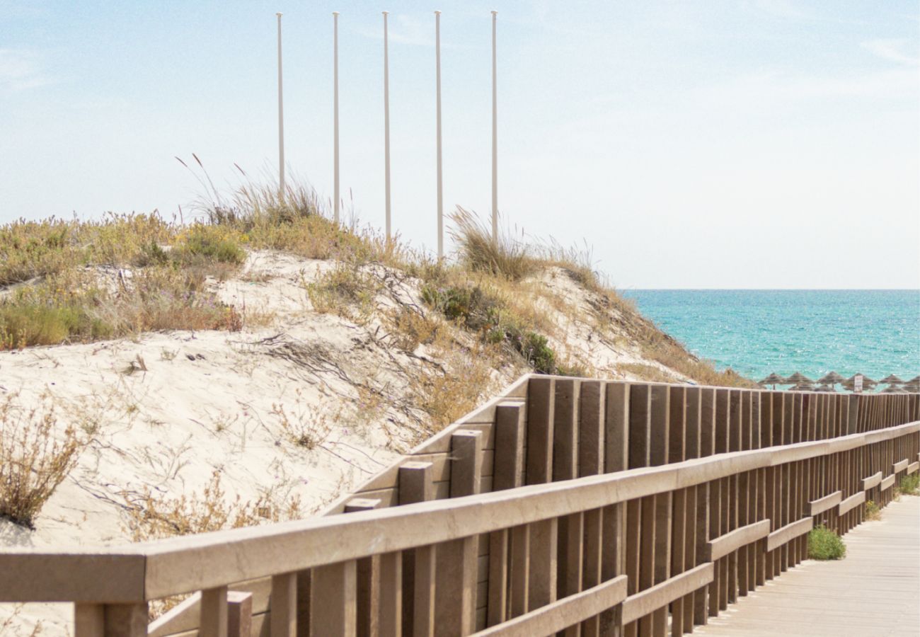 Wooden boardwalk leading directly to the white sandy beach in Troia at Pool Beach & Golf Troia.