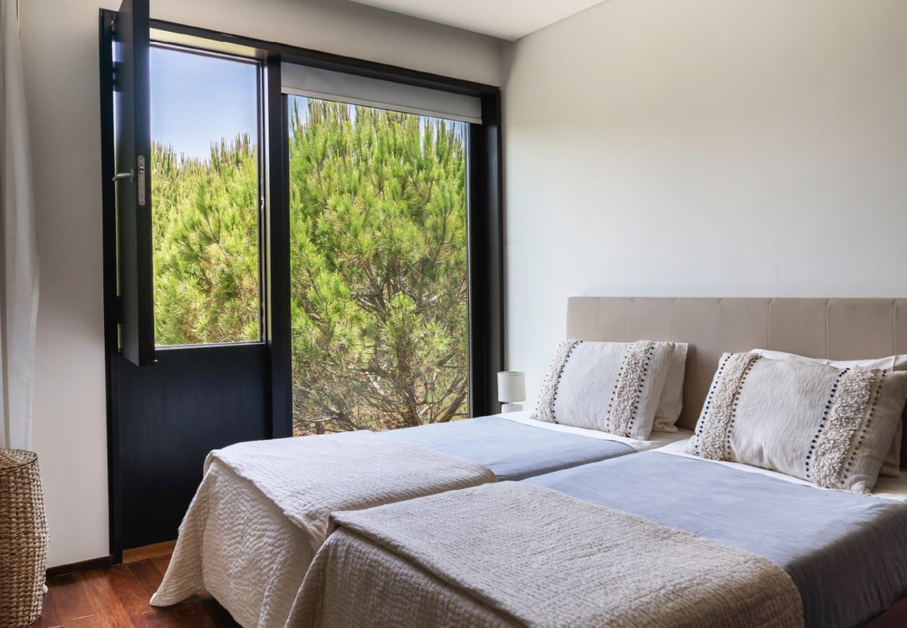 Modern bedroom with double bed, clean decor, and garden view at Pool Beach & Golf Troia.