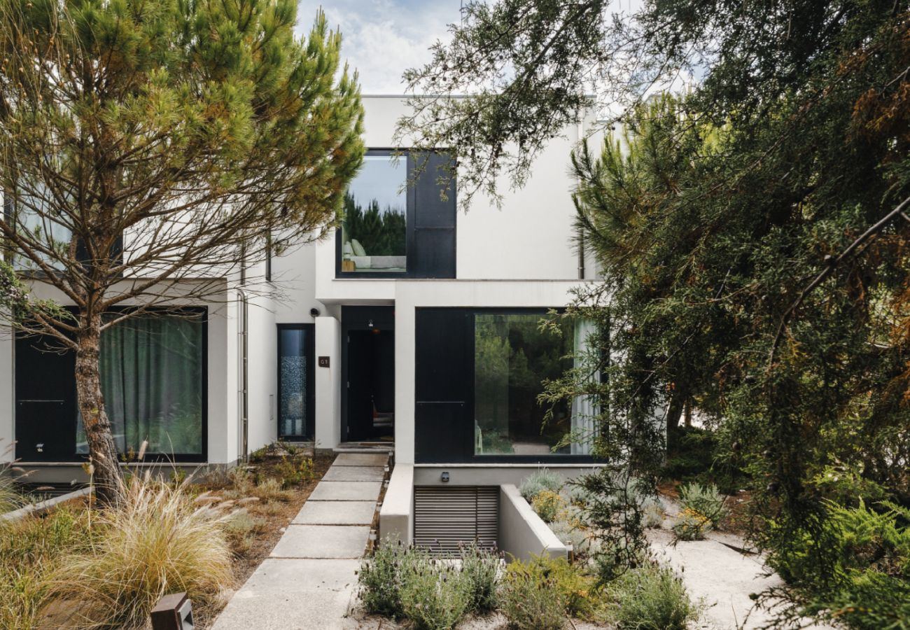 Modern facade of Pool Beach & Golf Troia with decorative garden and surrounding trees.