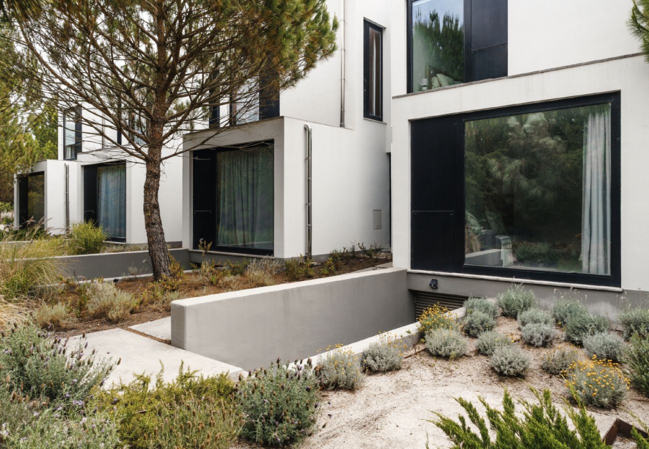 Modern facade of Pool Beach & Golf Troia with decorative garden and surrounding trees.