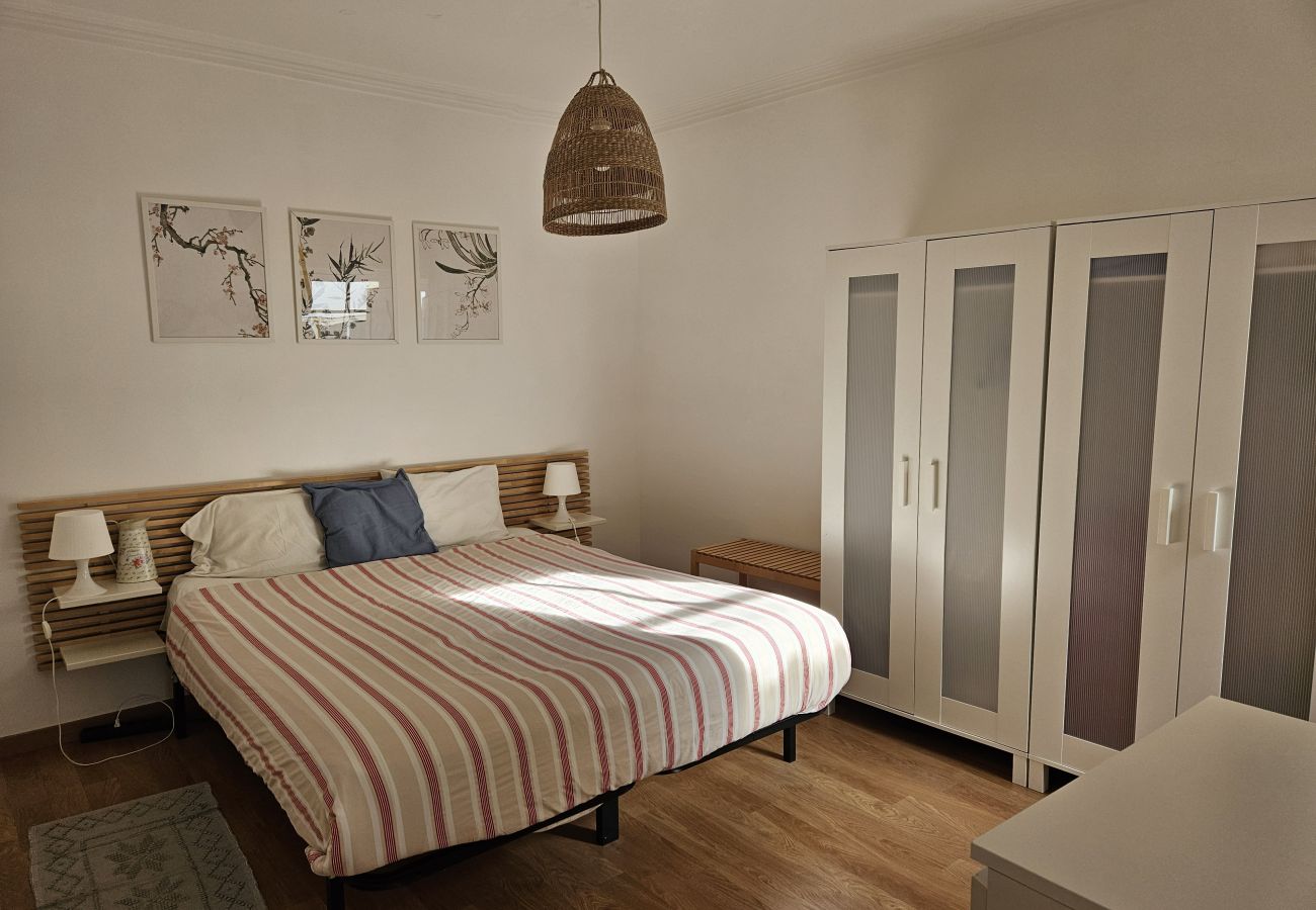 Spacious bedroom with a comfortable bed, large wardrobe, and minimalist decor.