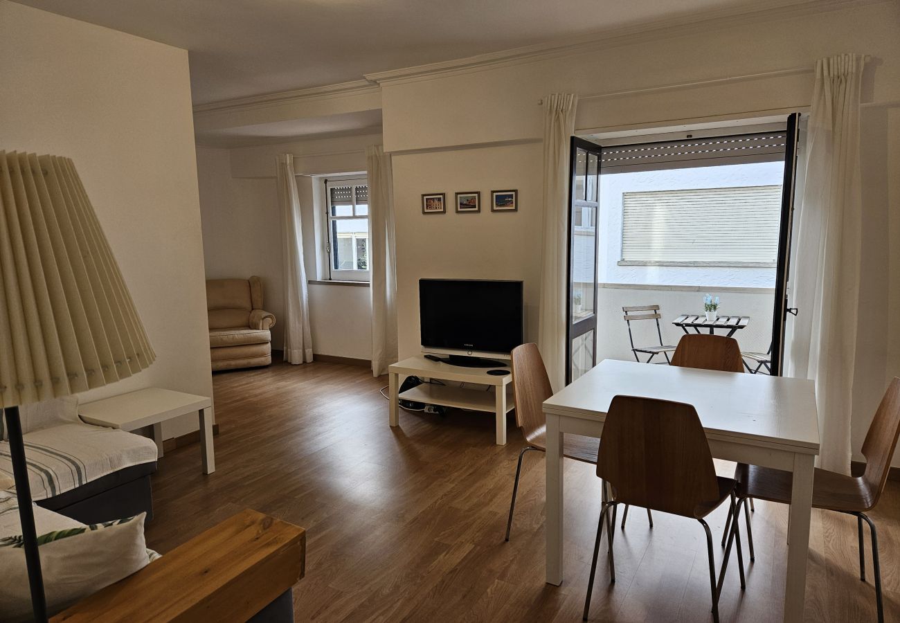 Bright living room with a dining table for four and street view in the historic center of Cascais.