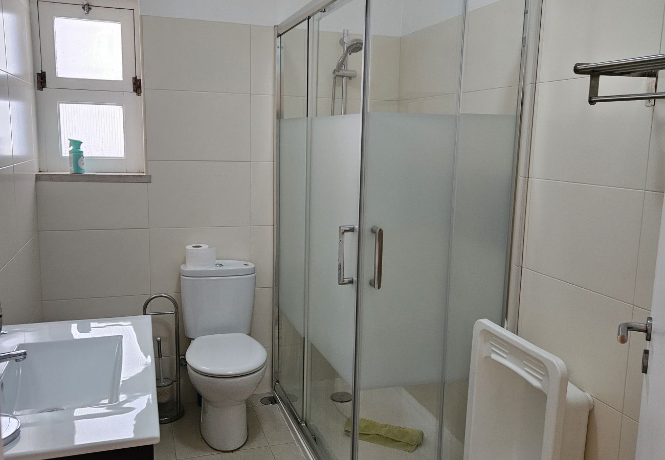 Stylish bathroom with glass shower, spacious sink, toilet, and window for natural ventilation.