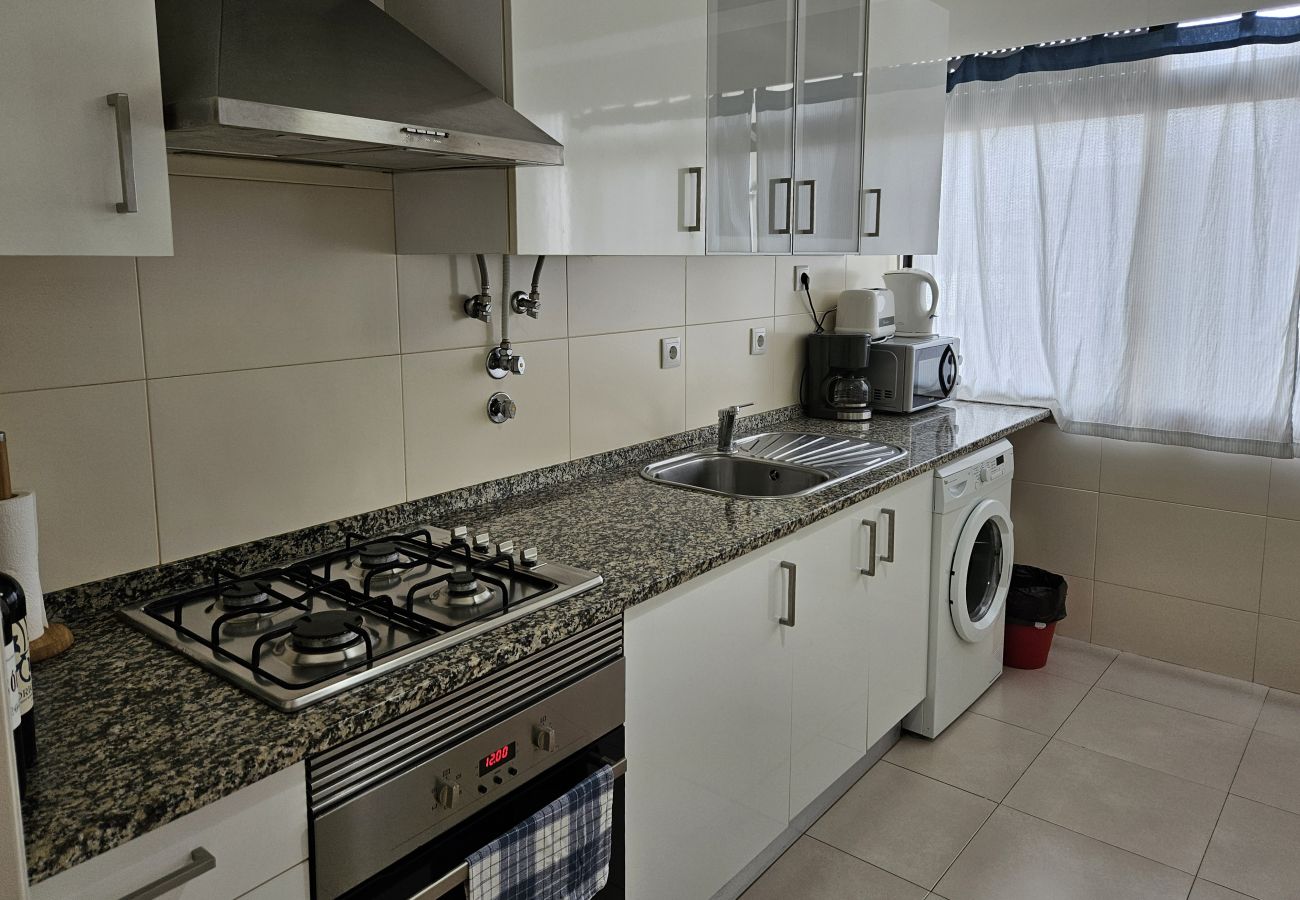 Functional kitchen with a modern stove, white cabinets, and a sink with an exterior view.