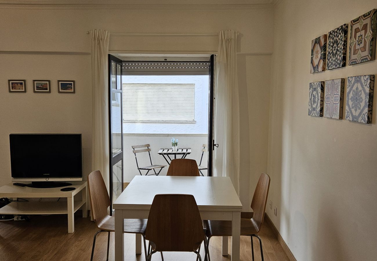 Functional dining space with a wooden table, TV, and a large window for natural light.