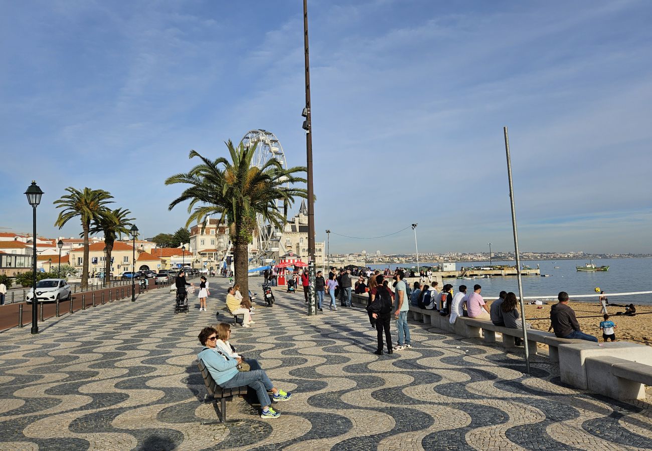 Seaside walkway in Cascais, featuring palm trees, benches for relaxation, and a beautiful view of the harbor and boats.