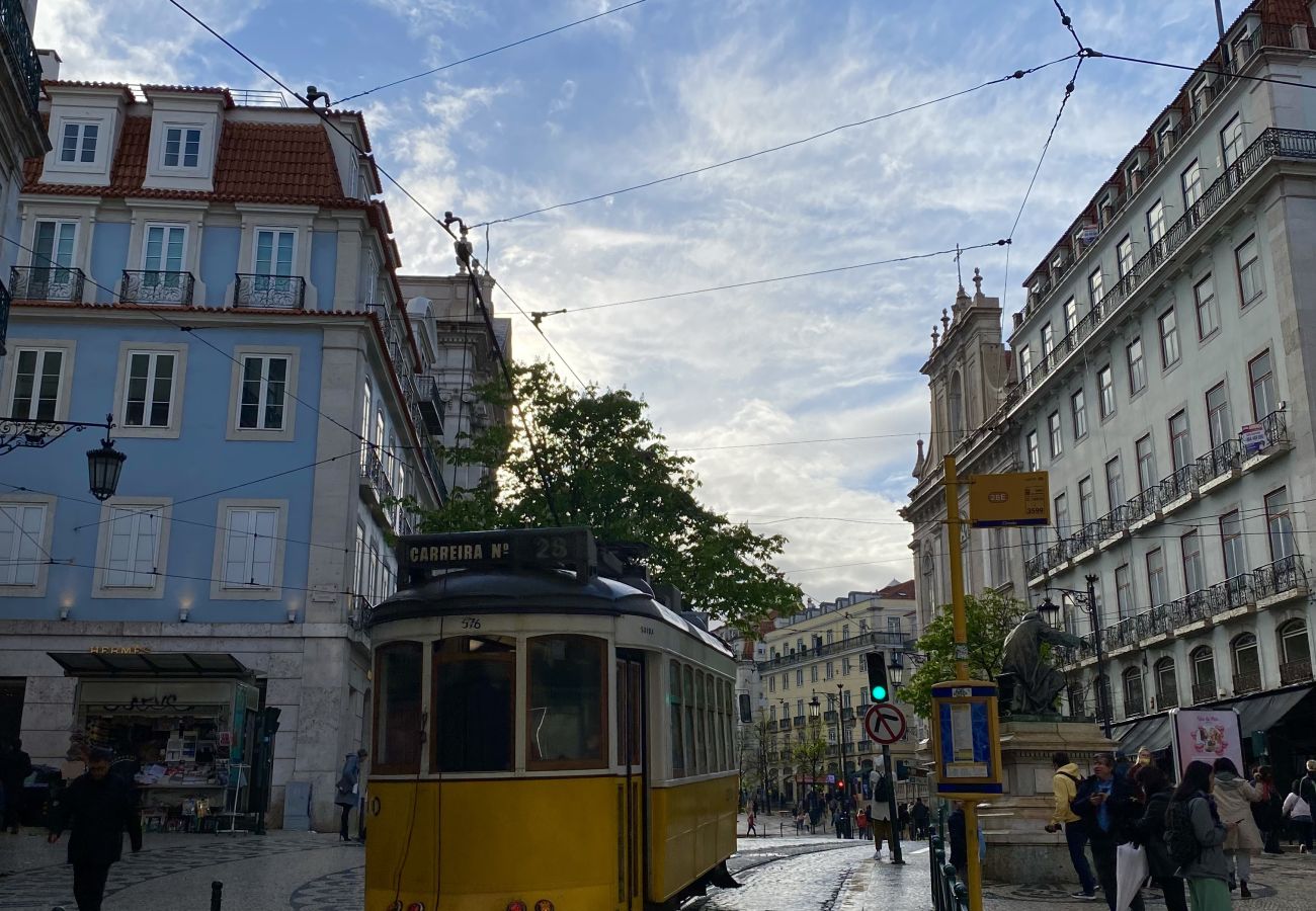 Yellow tram running through the streets of Lisbon at sunset, with historic architecture and a blue sky in the background.