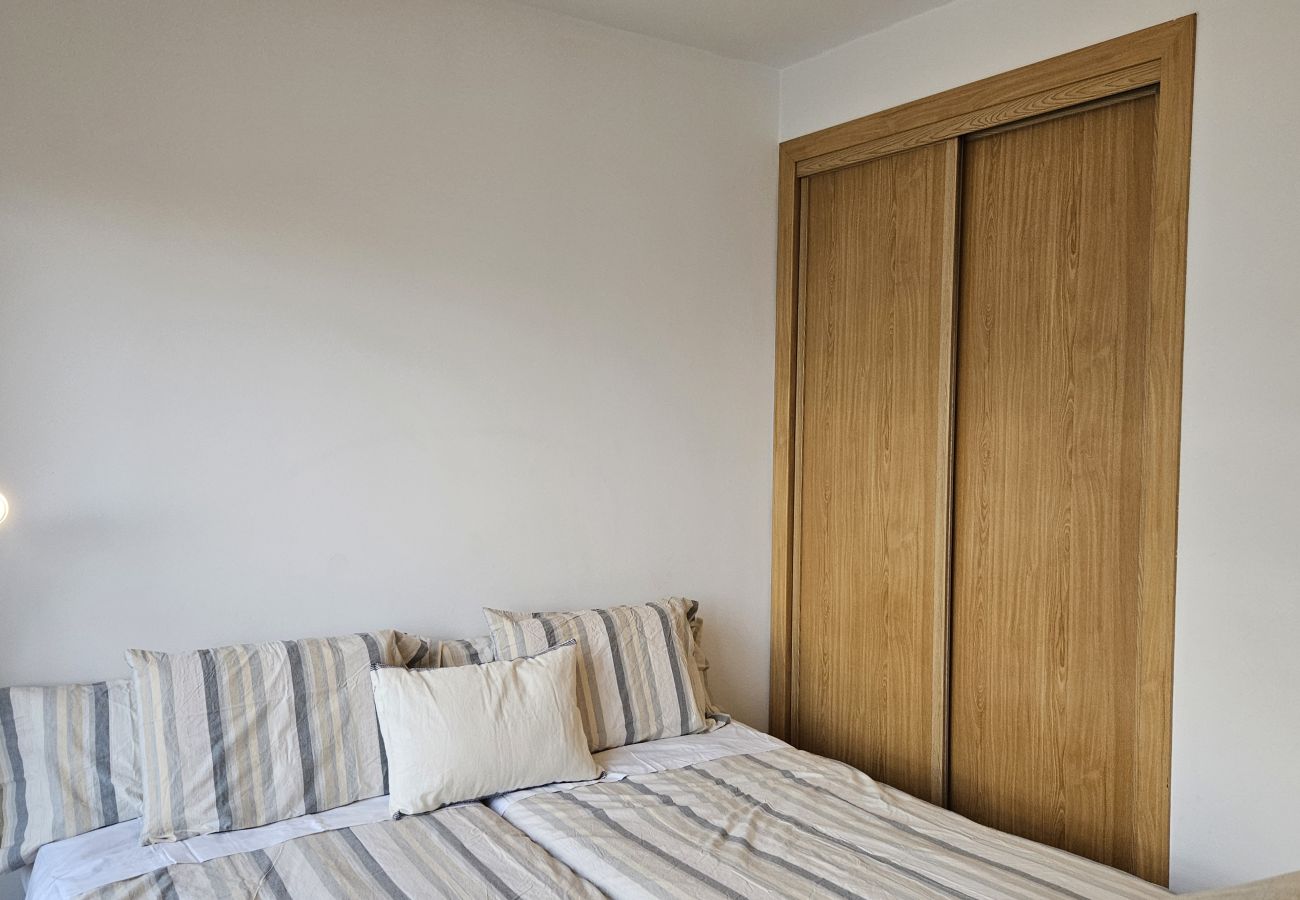 Modern bedroom with a double bed, neutral-tone bedding, and cozy lighting.