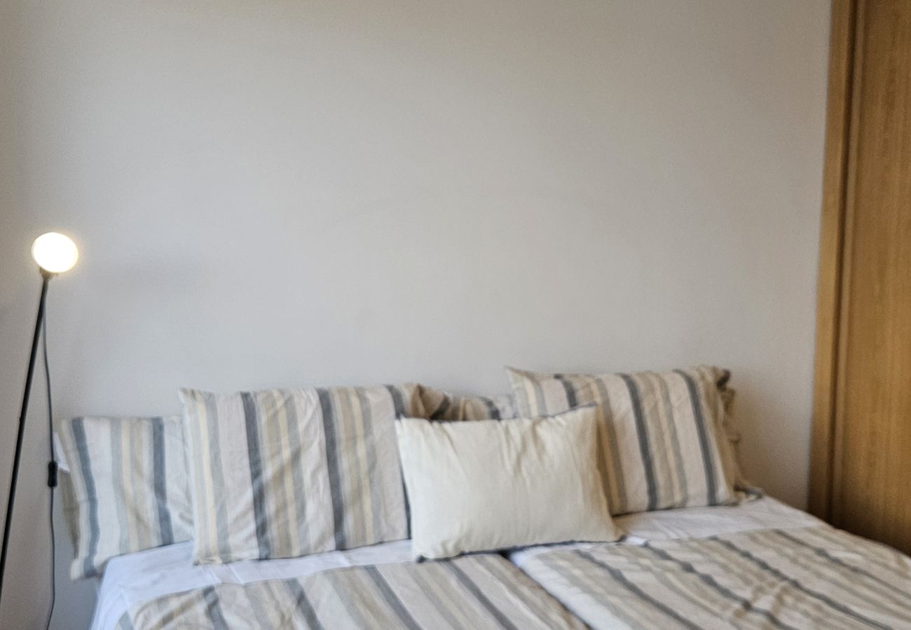 Comfortable bedroom with a double bed, striped bedding, and soft lighting.