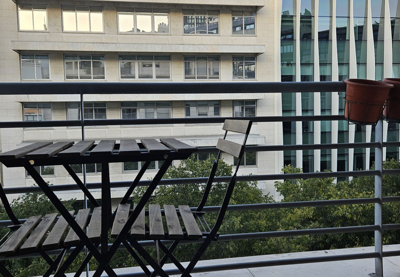 Small terrace with hanging plant pots and wooden furniture.