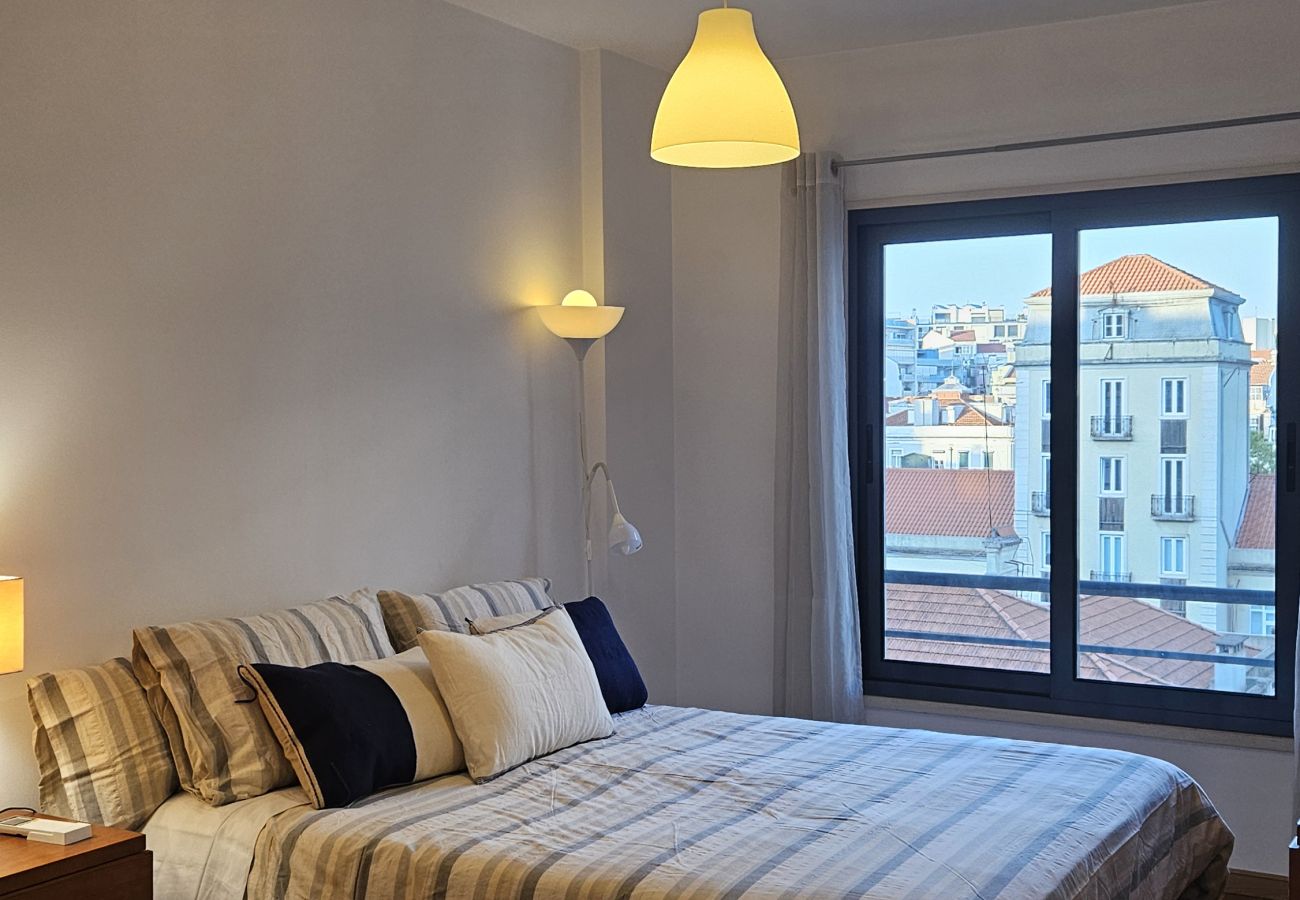 Bedroom with a king-size bed, minimalist decor, and large windows with natural light.