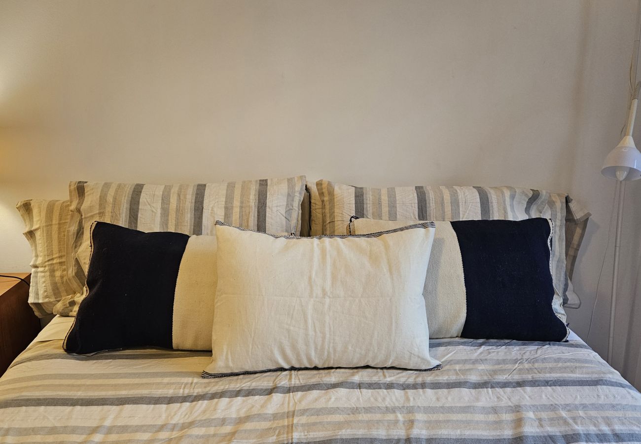 Double bed with stylish pillows, bedside lamp, and cozy lighting.
