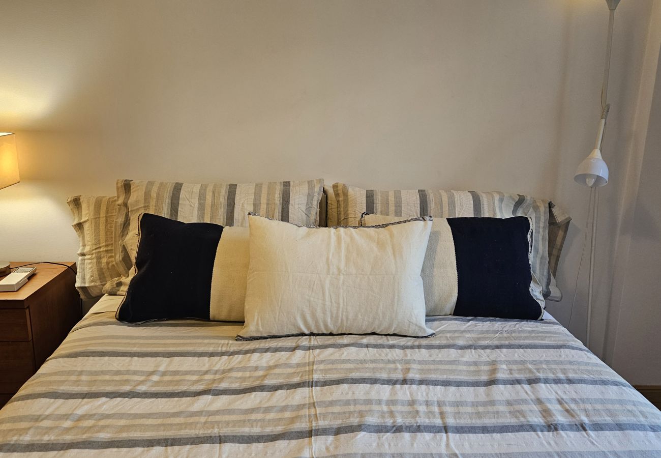 Double bed with striped bedding, decorative pillows, and soft lighting.