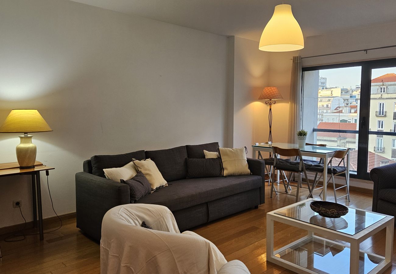 Spacious room with a comfortable sofa, white armchairs, dining table, and a balcony view.