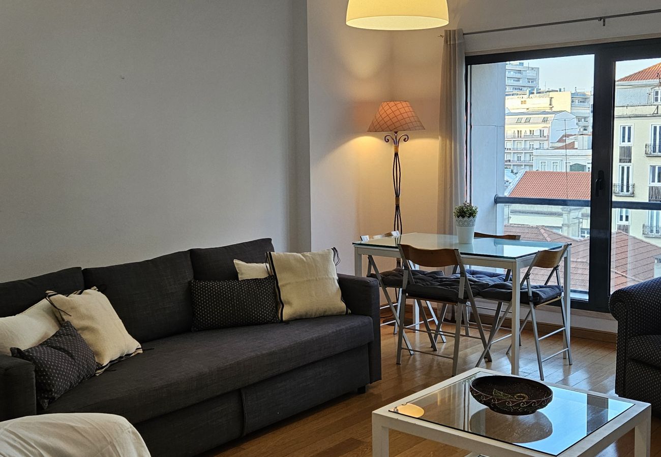 Spacious room with a comfortable sofa, white armchairs, dining table, and a balcony view.